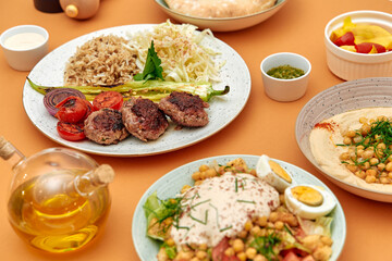 A Beautiful Spread of Mediterranean Cuisine Featuring Grilled Meat Patties, Flavorful Hummus, Fresh Vegetables, and Aromatic Rice, Perfect for a Nutritious Meal