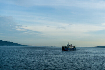 A ferry crosses the vibrant, blue Bali Strait under a sunny sky