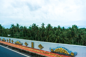 Beautiful Balinese ornaments adorn a serene roadside wall, showcasing the island's unique artistic heritage and culture