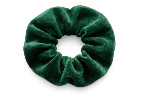 Green velvet scrunchie displaying soft, plush fabric texture, sitting against minimalist transparent backdrop - Powered by Adobe