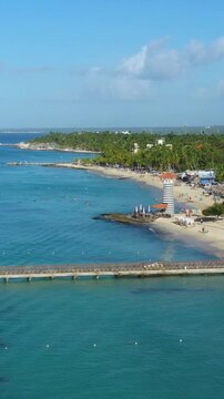 Dominicus beach at Bayahibe with Caribbean sea sandy seashore, lighthouse and pier. Dominican Republic. Aerial view from drone. Vertical footage