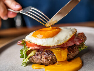 Dynamic Close-up: Fork Gently Piercing the Runny Yolk of a Sunny-Side-Up Egg

