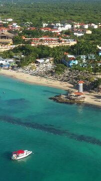 Dominicus beach at Bayahibe with Caribbean sea sandy seashore, lighthouse and pier. Dominican Republic. Aerial view from drone. Vertical footage