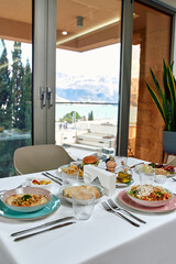 A Beautifully Arranged Outdoor Dining Table with Gourmet Meals Overlooking a Scenic View of Mountains and Water