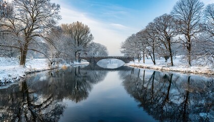 snowy river view with a bridge bare trees line the banks reflecting in the water