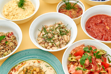 A Vibrant Spread of Delicious, Healthy Dishes Featuring Beans, Salads, Hummus, and Fresh Ingredients Served in Charming Bowls on a Colorful Background