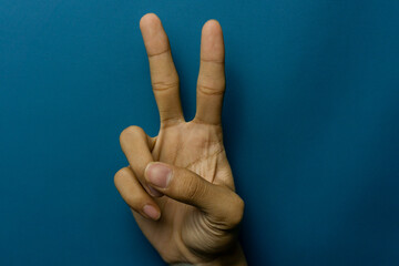 Hand showing the number two against a blue backdrop