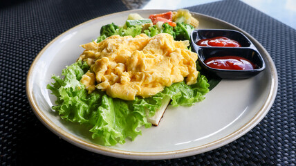 Freshly cooked golden yellow scrambled eggs served hot on a plate with vegetables and condiments. Perfect for breakfast, culinary blogs, food styling, and recipe illustrations. Close up