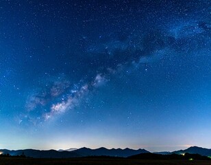 Fototapeta premium Panoramic night sky with Milky Way galaxy over mountain silhouettes, filled with stars in a clear atmosphere