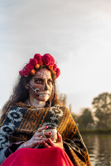woman characterized as La Catrina on a trajinera boat during sunrise in the canals of Xochimilco, Mexico. 