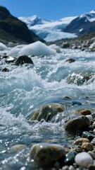 Rushing stream with clear water flowing over rocks, set against a backdrop of glaciers and mountains under a bright blue sky.
