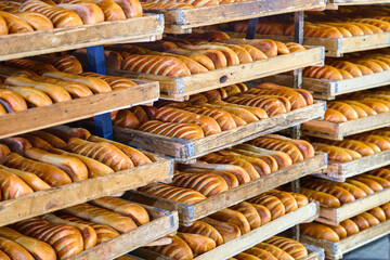 Freshly baked bread rolls arranged in wooden trays cooling after baking in a local bakery kitchen