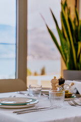 Elegant Dining Table Setting with Glasses, Cutlery, and Decorative Elements Overlooking Scenic View and Natural Greenery