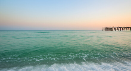 Obraz premium Serene Ocean Horizon with Distant Pier at Dusk