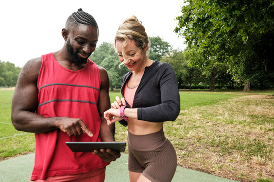 Personal trainer showing fitness results on tablet in park