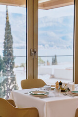 A Serene Dining Experience with Scenic Views Overlooking Mountains and Water, Featuring Elegant Table Settings and Modern Decor in a Bright, Airy Space
