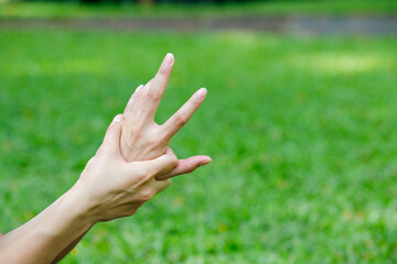 Close-up of a hand stretching exercise in the park. Gentle outdoor activity for joint flexibility, relaxation, and finger mobility in a green natural setting.
