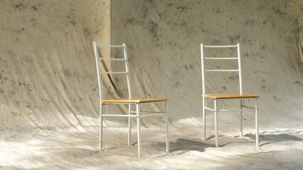 Two minimalist metal chairs with wooden seats placed on wrinkled fabric background. Natural...