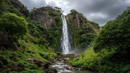 Obraz premium Majestic Waterfall Cascading Down Lush Green Mountainside