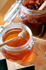 A Close-Up Look at Delicious Natural Honey and Rich Jam in Jars Enhanced with Wooden Dippers and Inviting Colors on a Rustic Wooden Surface
