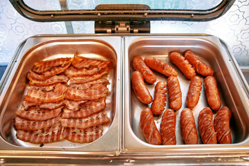 A Delicious Display of Crispy Bacon Strips and Grilled Sausages in a Buffet Setting, Perfect for Breakfast Enthusiasts