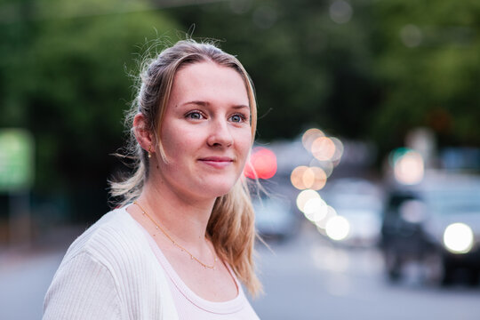 A 24 year old woman with a ponytail in an urban setting at dusk