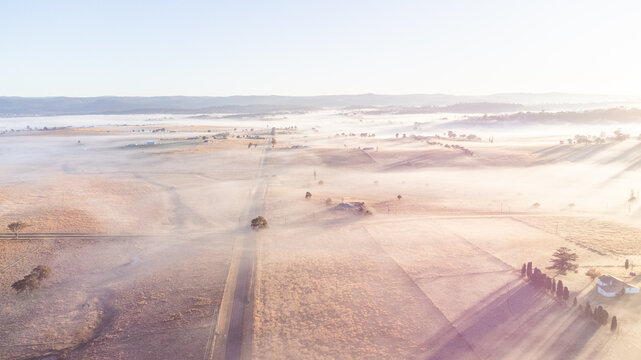 An aerial photo of a winter's scene with a mist and frosty fields