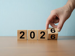 Hand turning wooden blocks from 2026 to 2027 symbolizing change