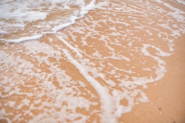 Gentle waves lapping at sandy shore during a sunny afternoon by the ocean