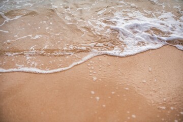 Waves gently lap against a sandy shore at sunset on a tranquil beach