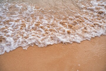 Waves gently lapping on a sandy beach during a calm afternoon by the shore