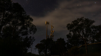 Telecommunications tower illuminated at night with starry background, wide angle