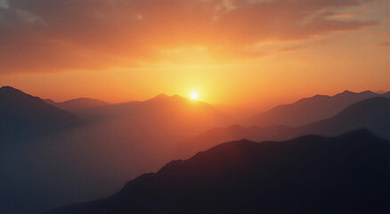 Fototapeta premium Dramatic sunset over mountains with golden hour light casting long shadows, mist hovering between peaks, creating an ethereal and calm atmosphere. Shot with wide angle lens at f/16 for deep focus and 
