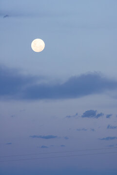 Moon at sunset against a blue evening sky and clouds