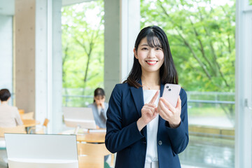 Obraz premium オフィスでスマホを使うビジネスウーマン