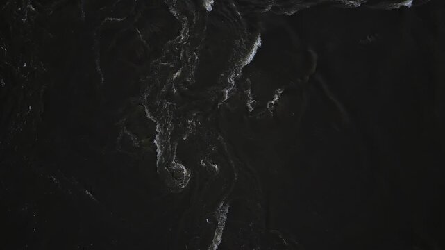 The turbulent swirling waters of the Mississippi River as seen from above. The dark muddy water is rushing by, creating an interesting visual where the undertow and swirls can be seen