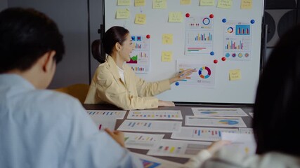 Dynamic young asian businesswoman presents important statistical insights to her engaged colleagues, analyzing data presented on a whiteboard in the office, marketing, financial report, teamwork - Powered by Adobe