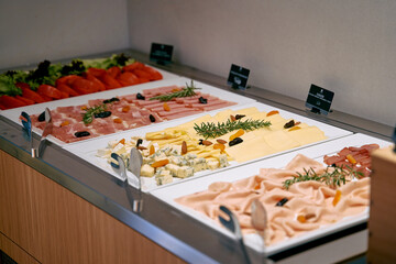 A Varied Selection of Fresh Charcuterie and Cheeses Displayed Elegantly on a Buffet Table with Garnishes and Accompaniments for a Culinary Experience