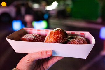 sugar covered hot jam donuts in takeaway tray at night market event