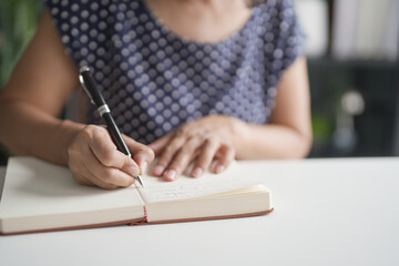 Senior Asian woman Work from home making list or writing diary.
