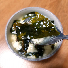 A close-up image of a spoonful of creamy seaweed soup with soft white tofu. The soup itself is a...