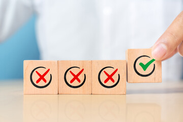 Hand pushing green correct sign symbol in front of Red Cross sign on wooden block cube for business proposal and document approve concept
