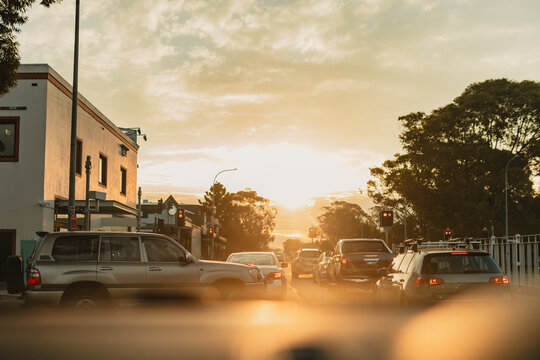 Vehicle entering busy road along urban street in vibrant afternoon sunlight