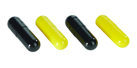 Bulk black and yellow capsule pills isolated on white background.