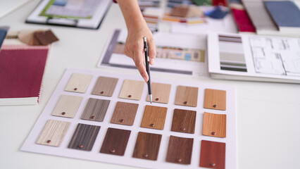 Architect designer professional selects material samples for home interior renovation project using color swatches wood textures at modern design office studio