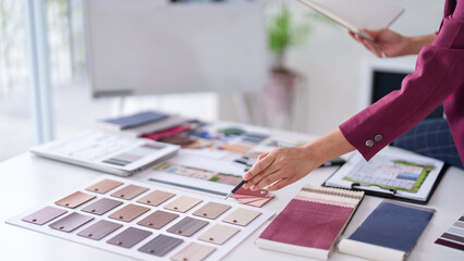 Adult Asian hand chooses material samples interior design office architect selects color palettes...