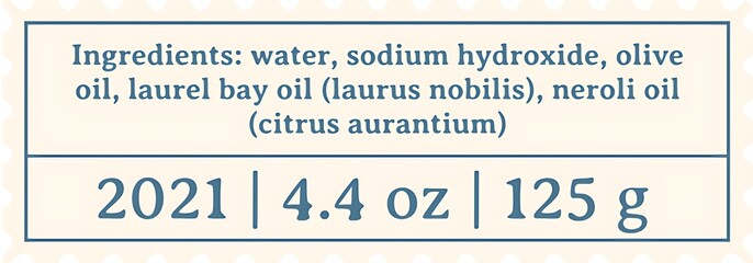 Close up of a soap label showing ingredients water sodium hydroxide olive oil laurel bay oil and neroli oil isolated on white background