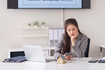 Asian adult woman calculating property sales insurance costs home loan financial planning at modern office