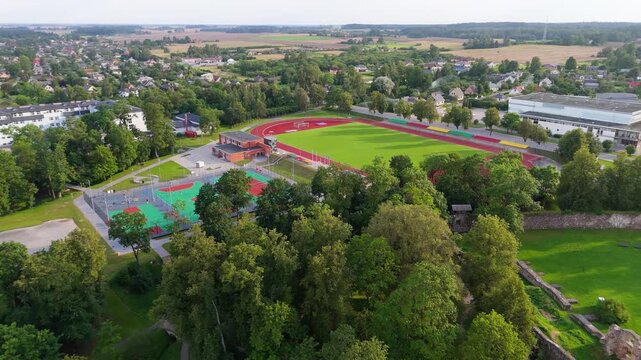 Drone Sunset View Over Dobele City Aerial Timelapse of School, Stadium and Historic Castle Ruins in Warm Evening Light, Capturing the Peaceful Atmosphere of Latvian Urban and Cultural Landscape