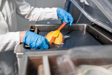 Industrial food packaging. Worker in sterile clothing labeling food product.